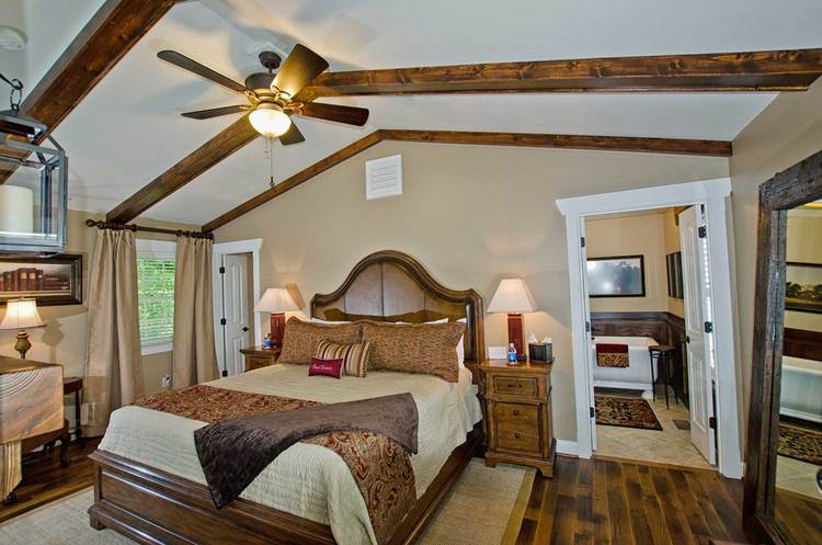 king bedroom with hardwood floors, wood beamed ceilings, and tan walls