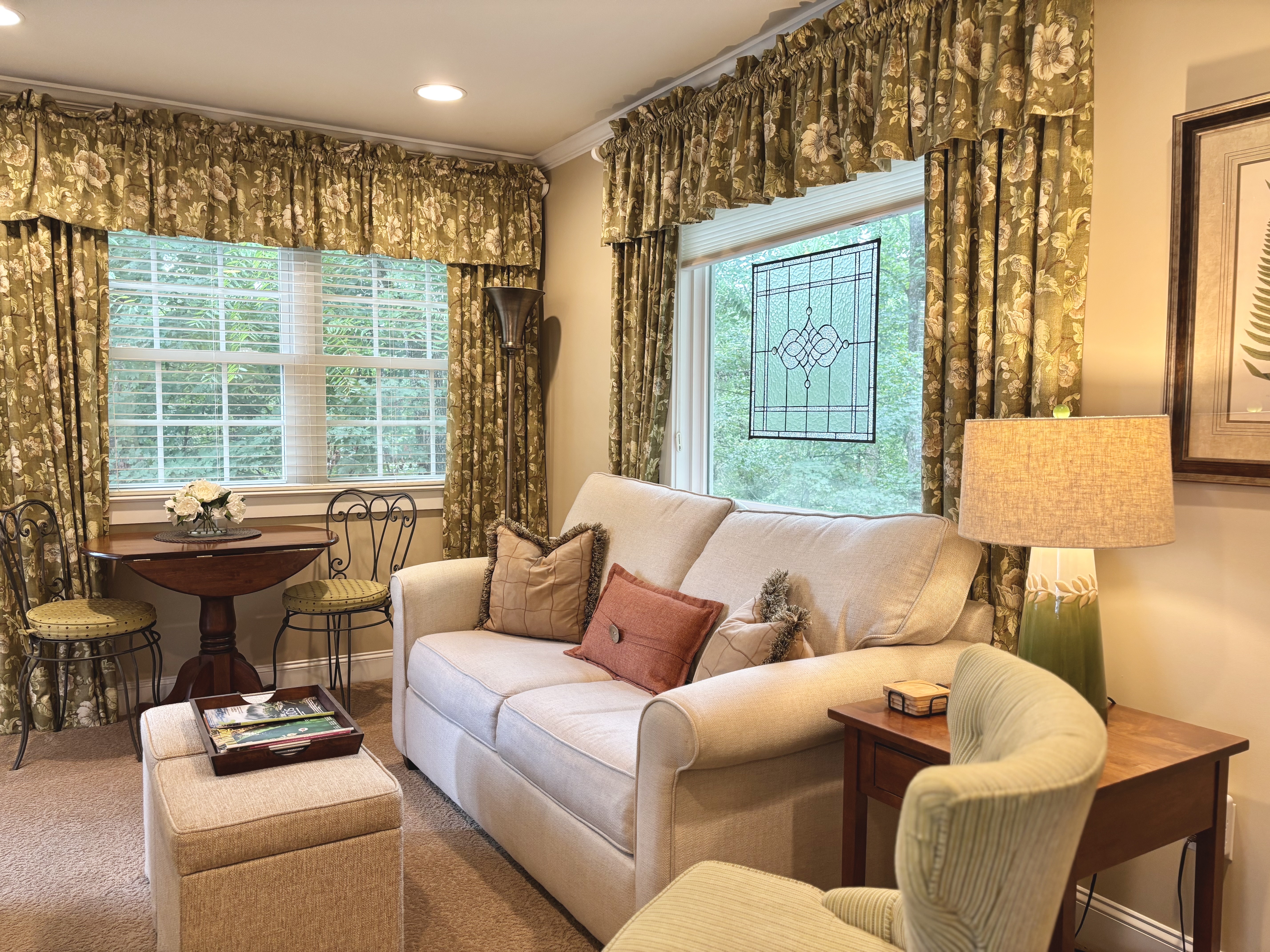 spacious seating area featuring twin pull-out sofa and green window curtains