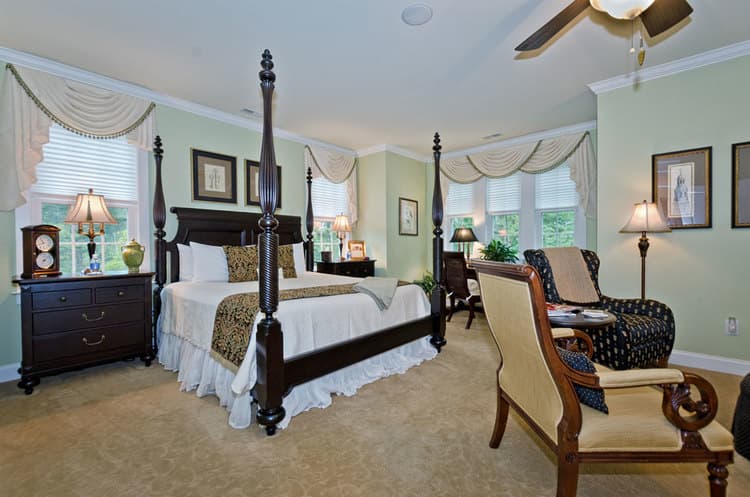 spacious bedroom featuring king bed, light green walls, and a seating area