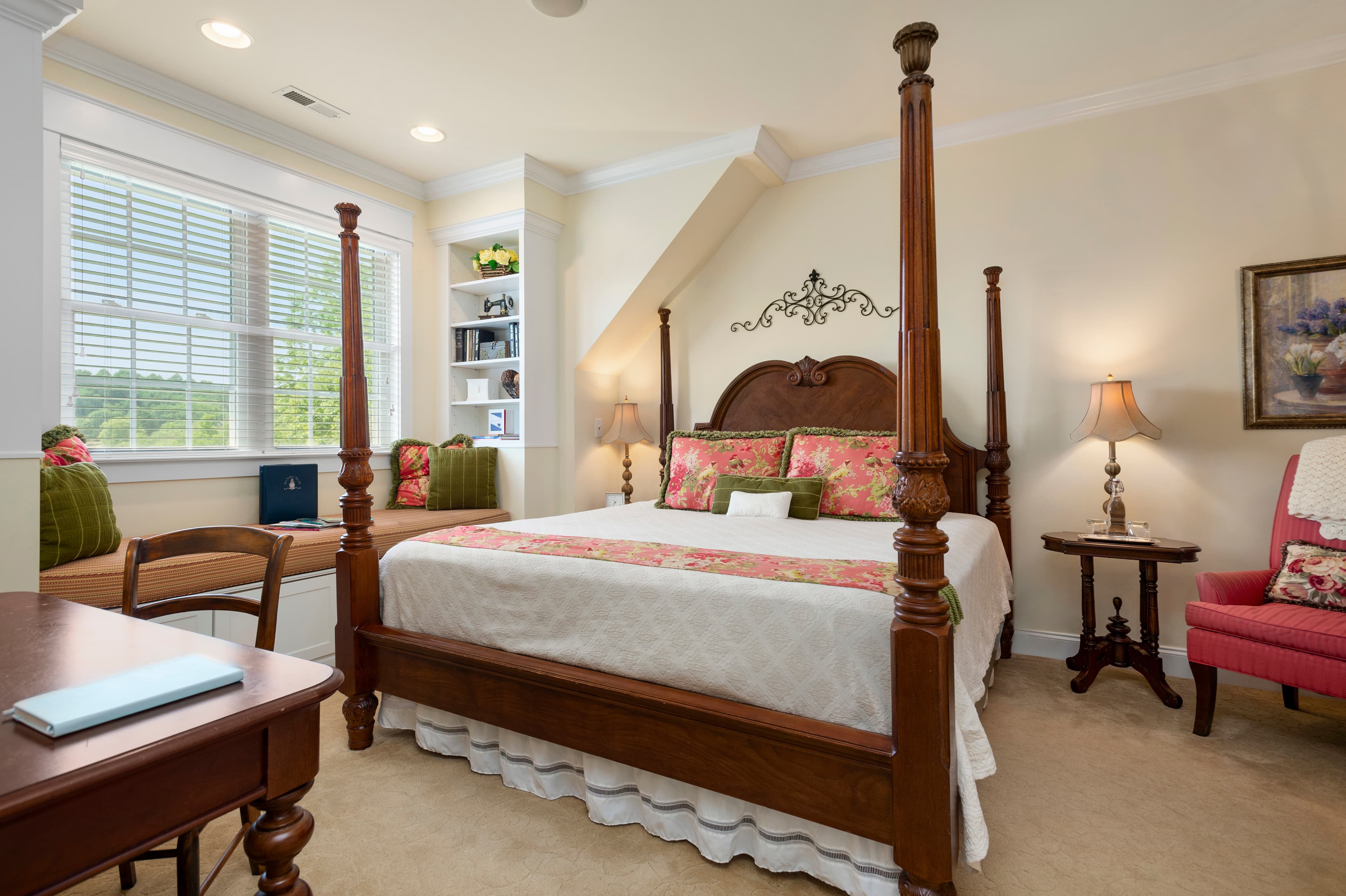 King poster bed and pink armchair in bedroom
