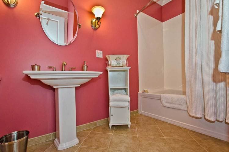 bathroom featuring pink walls, white furnishings, and bathtub