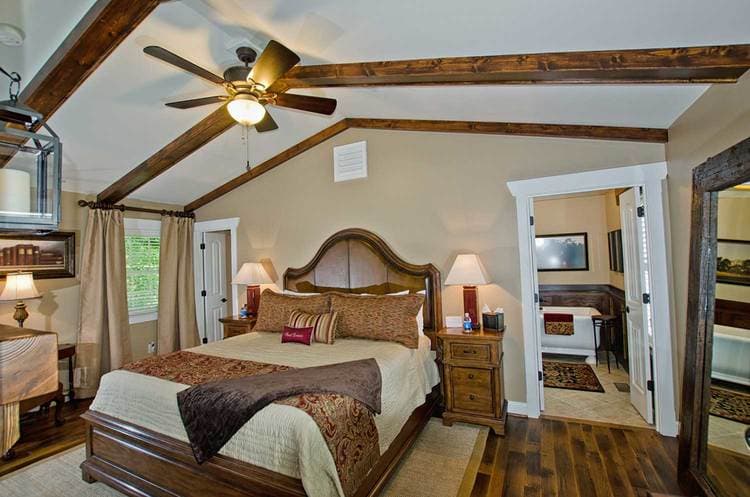 king bedroom with hardwood floors, wood beamed ceilings, and tan walls