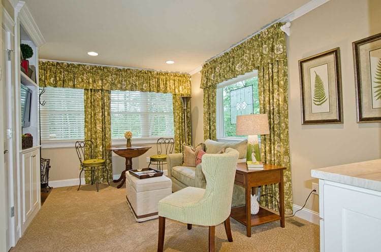 spacious seating area featuring twin pull-out sofa and green window curtains