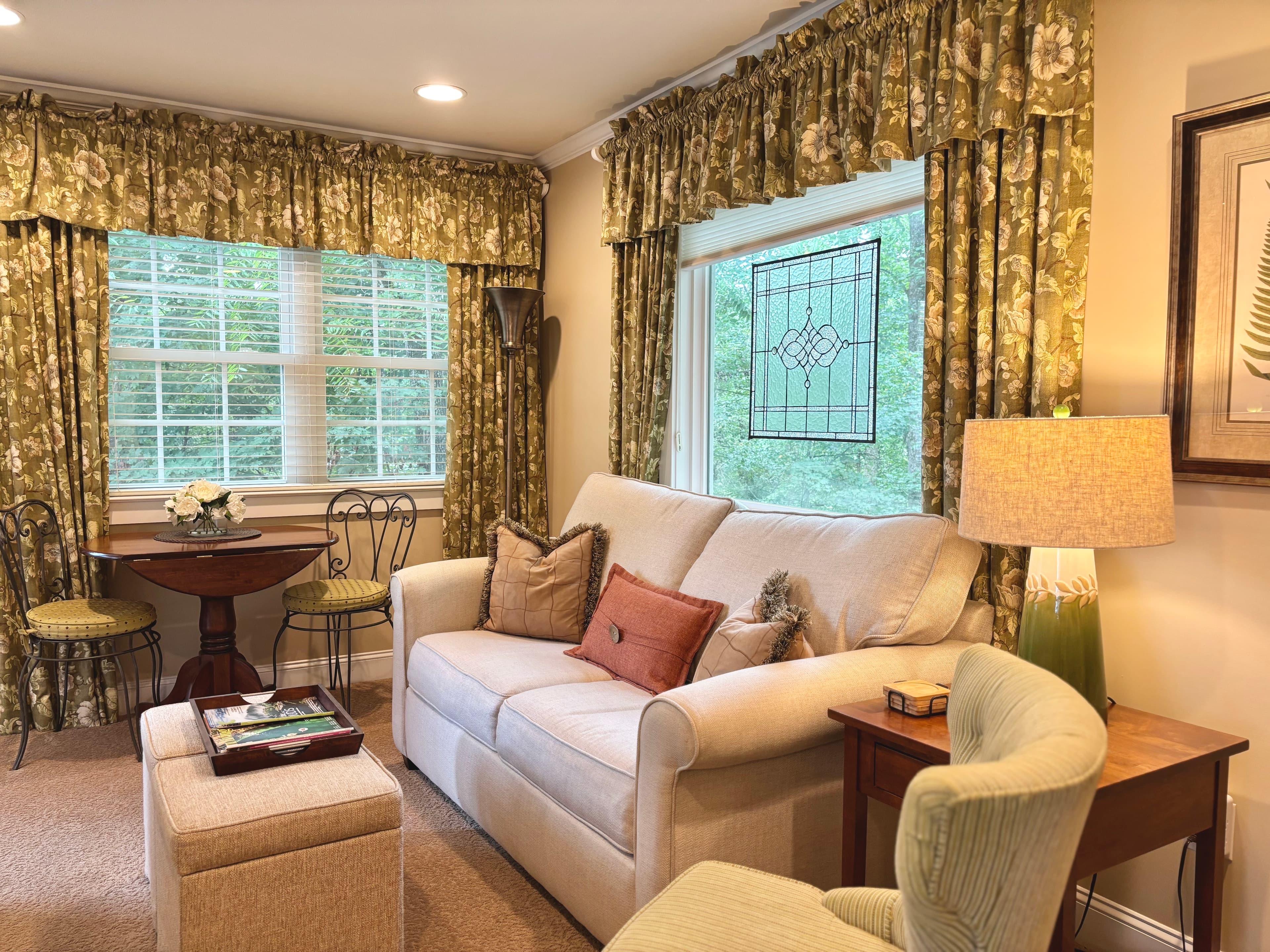 spacious seating area featuring twin pull-out sofa and green window curtains