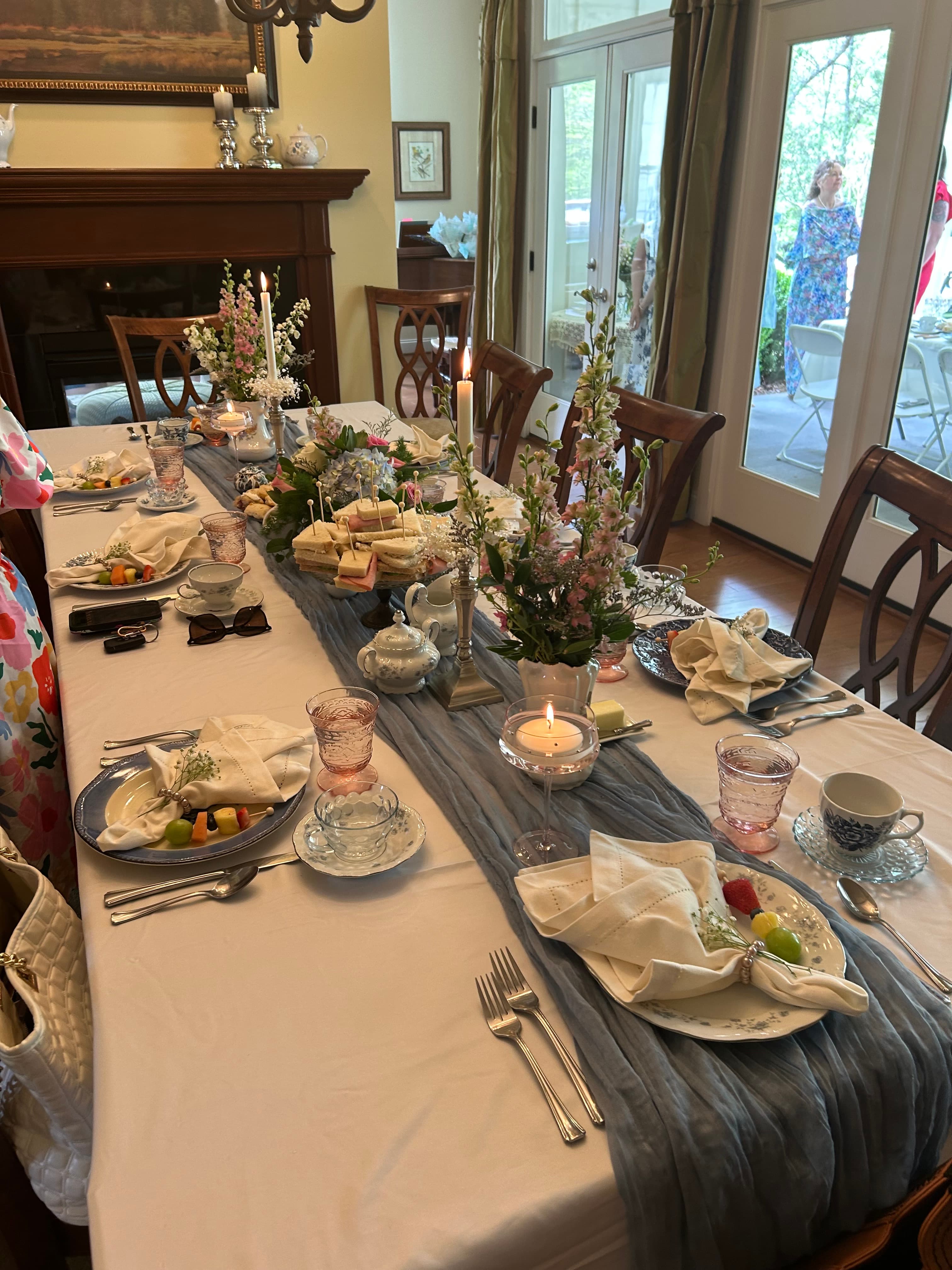A beautifully set dining table with floral centerpieces, candles, and an assortment of food items.