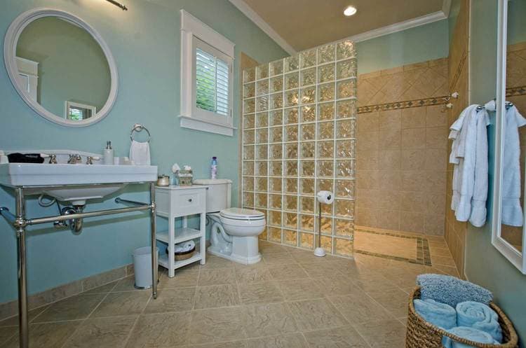 A modern bathroom featuring a glass block shower, white fixtures, and blue walls.